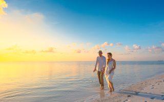 Couple Walking on Seashore Wearing White Tops during Sunset