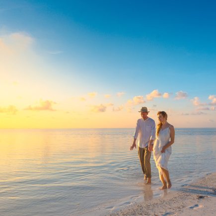 Couple Walking on Seashore Wearing White Tops during Sunset